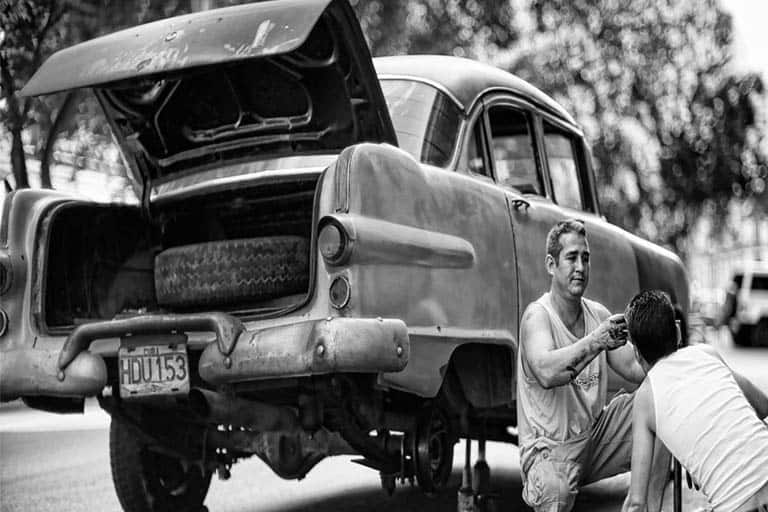 2 men trying to fix a car