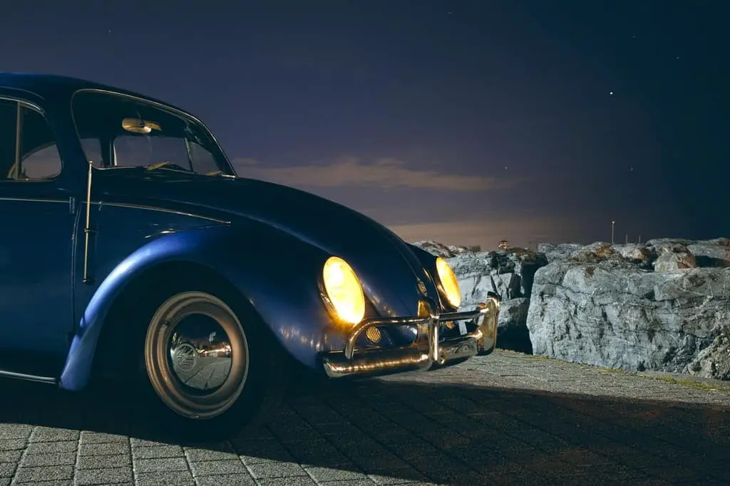  a blue Volkswagen car with lights on during a starry night